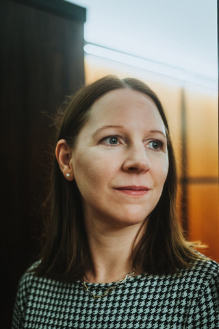 Eine Dame in Geschäftskleidung blickt zur Seite.