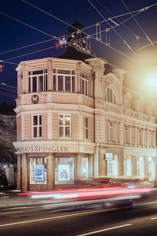 Ein schlossähnliches historisches Gebäude hinter den Umrissen von fahrenden Autos und Stromleitungen.
