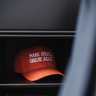 Eine rote Kappe mit der Aufschrift "Make America great agian" liegt in einem Regal.