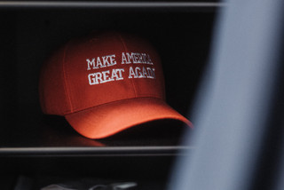 Eine rote Kappe mit der Aufschrift "Make America great agian" liegt in einem Regal.