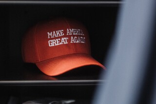 Eine rote Kappe mit der Aufschrift "Make America great agian" liegt in einem Regal.