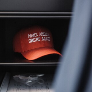 Eine rote Kappe mit der Aufschrift "Make America great agian" liegt in einem Regal.