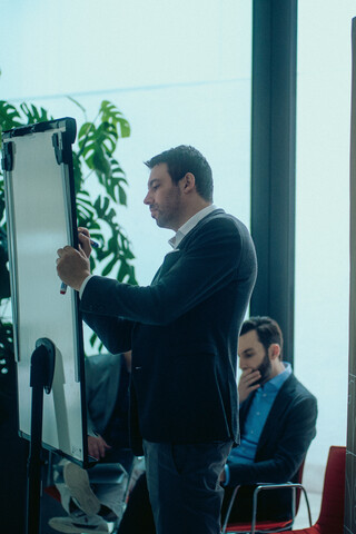Ein Herr in Anzug beschreibt ein Flipchart.