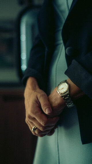 Detailaufnahme zweier sich berührender Hände einer Frau, die eine Uhr und einen Ring trägt.