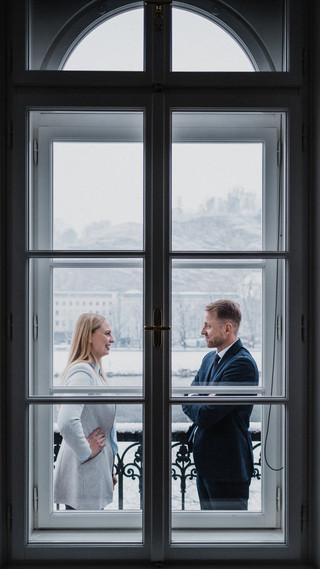 Hinter dem Fenster unterhalten sich eine Frau und ein Mann.