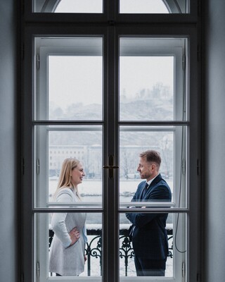 Hinter dem Fenster unterhalten sich eine Frau und ein Mann.
