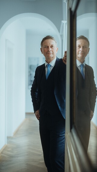 Mann im Anzug blickt steht im Türrahmen