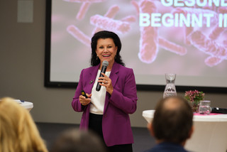 Prof. Anita Frauwallner, Gründnerin der Firma Omni Biotic, hält vor einem Publikum einen Vortrag in einem lila Sakko.