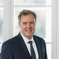 Oberkörper eines lächelnden Herren in Anzug.