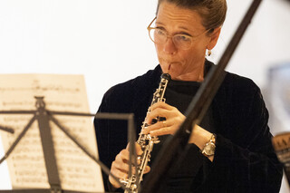Eine Dame hinter einem Notenständer bespielt ein Blasinstrument.