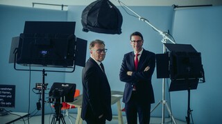 Dr. Nils Kottke und ein Mann stehen vor Aufnahmegeräten. Beide Männer schauen lächelnd in die Kamera.
