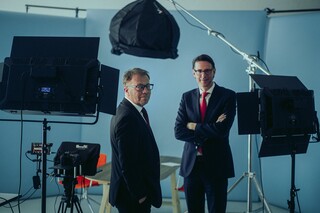 Dr. Nils Kottke und ein Mann stehen vor Aufnahmegeräten. Beide Männer schauen lächelnd in die Kamera.