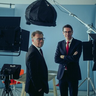 Dr. Nils Kottke und ein Mann stehen vor Aufnahmegeräten. Beide Männer schauen lächelnd in die Kamera.