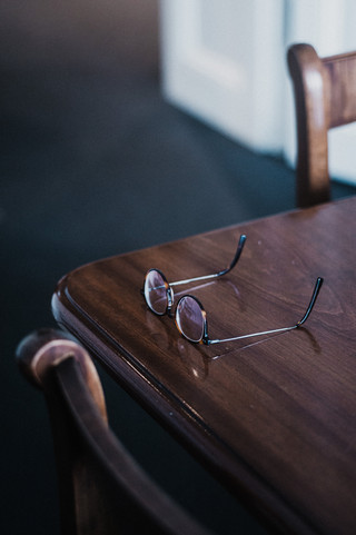 Auf einem Holztisch liegt eine Brille.