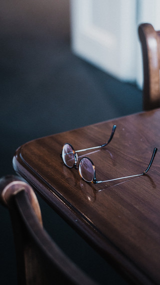 Auf einem Holztisch liegt eine Brille.