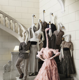 Webesujet des Bankhaus Spängler: Eine dunkel-gekleidete Familie mit Schwan-Köpfen steht auf einer Treppe. Eine Dame sticht besonders hervor - sie hat einen Flamingo-Kopf und trägt ein opulentes Kleid in rosa Farbe.