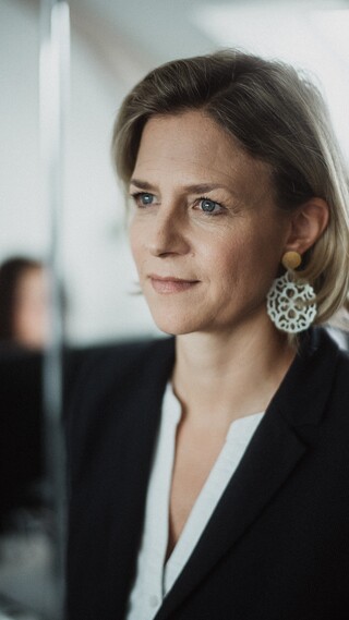 Eine Frau mit kurzen Haaren blickt nach vorne. 