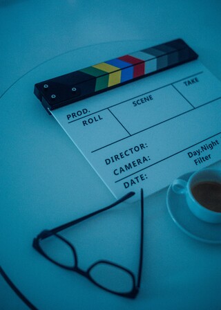 Auf einem Tisch liegen eine Brille, eine Filmklappe und eine Tasse Espresso – alles ist bereit für den Dreh.