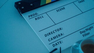 Auf einem Tisch liegen eine Brille, eine Filmklappe und eine Tasse Espresso – alles ist bereit für den Dreh.