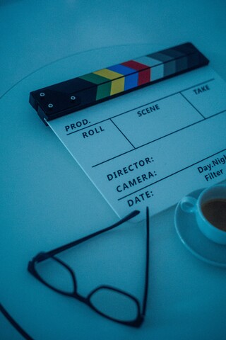 Auf einem Tisch liegen eine Brille, eine Filmklappe und eine Tasse Espresso – alles ist bereit für den Dreh.