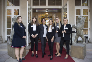 Sechs Frauen (alle schwarz-weiß gekleidet) stehen im äußeren Eingangsbereich eines historischen Gebäudes (Kavalierhaus Klessheim, Salzburg). Alle Lächeln freundlich.