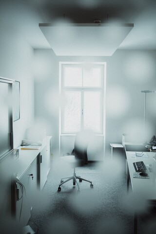 In einem nebligen Raum, ein Schreibtisch und ein Sessel.