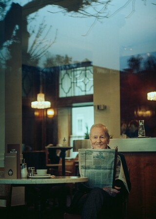 Ein älterer Herr liest eine Zeitung in einem Kaffeehaus.