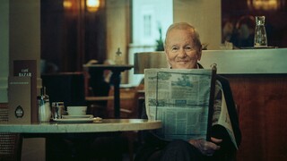 Ein älterer Herr liest eine Zeitung in einem Kaffeehaus.