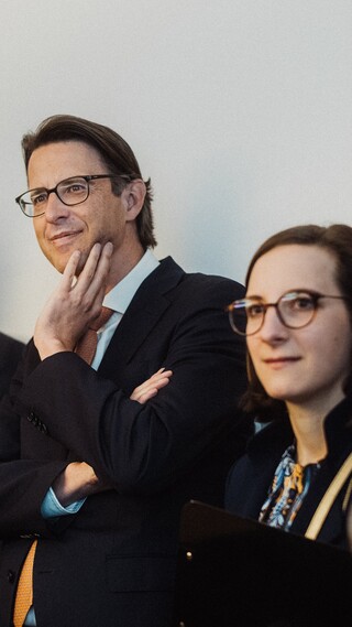 Personen in Geschäftskleidung blicken gespannt in eine Richtung.