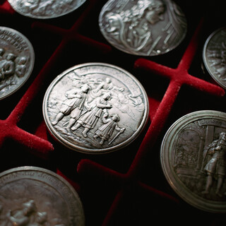 Schraubmünzen liegen in einer samtigen roten Box. Der Blick von oben zeigt die schön gestalteten, detailreichen Oberflächen der Münzen.