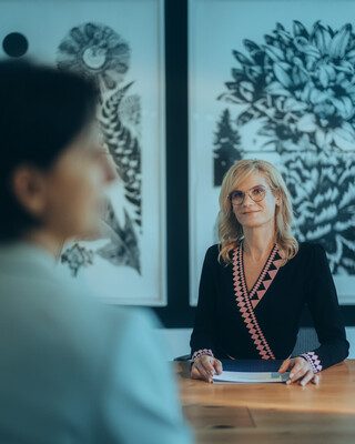 Eine Kundin und eine Beraterin sitzen am Tisch und schauen sich gegenseitig an.