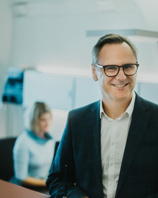 Ein Herr in Geschäftskleidung lächelt.