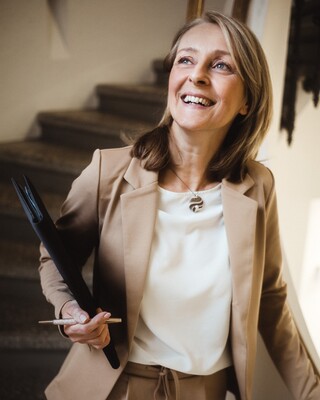 Eine Frau steht lachend auf dem Treffen und hält etwas in der Hand.
