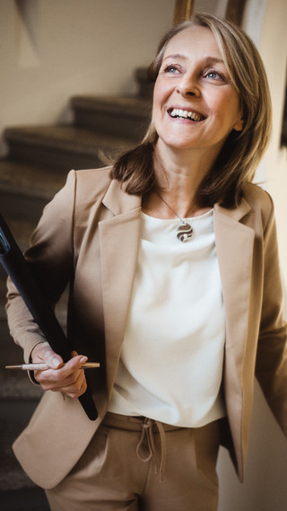 Eine Frau steht lachend auf dem Treffen und hält etwas in der Hand.