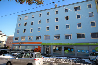 Einfaches Gebäude mit blauer Fassade von der Nähe mit vielen weißen Fenstern. Im Erdgeschoss sind die "Fahrschule Zaunschirm" und "Gebäude Reinigung" beheimatet.