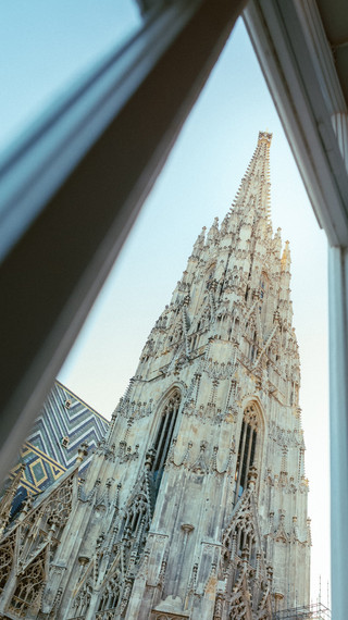 Blick durch ein Sprossenfenster auf den Turm eines Doms.