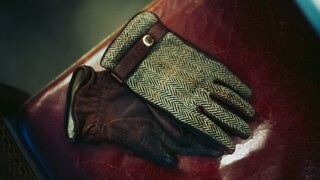 Ein Paar Handschuhe liegt auf einer mit rotem Leder bezogenen Bank.