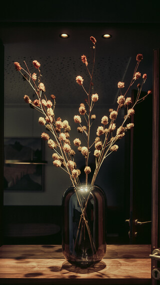 Detailaufnahme einer gläsernen Blumenvase; dahinter sind Bilder an der Wand zu erkennen.