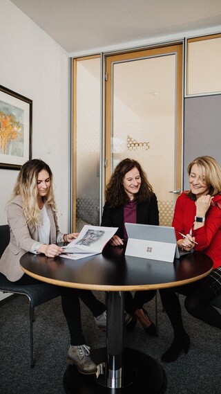 Ein Besprechungsraum, Frauen sitzen am schwarzen Tisch, besprechen.