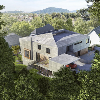 Blick von oben auf eine moderne Immobilie von außen in grauer Farbe. Das Wohnhaus ist in eine grüne Naturlandschaft eingebettet