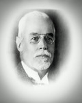 Schwarz-weißes Portraitfoto von einem älteren Herren mit vermutlich grauen Haaren und einem Bart, er trägt eine Brille.