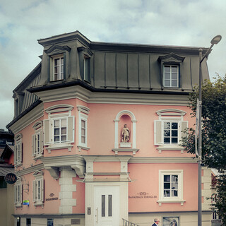 Ein historisches Gebäude mit rosafarbener Fassade beherbergt den Standort des Bankhaus Spängler in Kitzbühel.