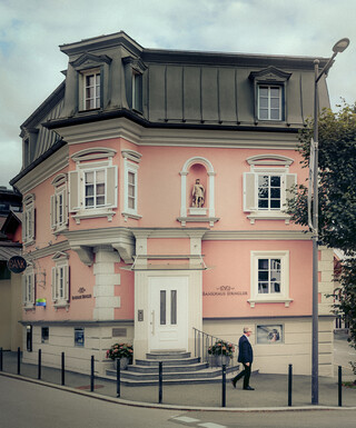 Ein historisches Gebäude mit rosafarbener Fassade beherbergt den Standort des Bankhaus Spängler in Kitzbühel.