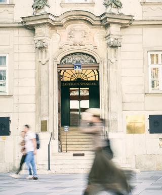 Äußere Eingangsfassade des Bankhaus Spängler am Stephansplatz in Wien. Im Vordergrund spaziert eine Frau vorbei.