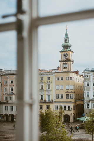 Blick durch ein Sprossenfenster auf eine Altstadt mit Kirchturm.