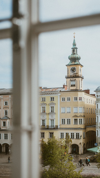 Blick durch ein Sprossenfenster auf eine Altstadt mit Kirchturm.