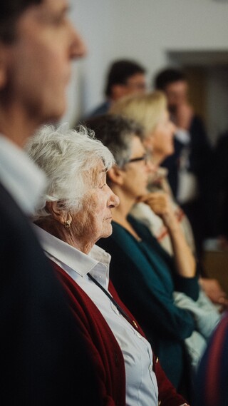 Eine Reihe an Personen in eleganter Kleidung sieht in die gleiche Richtung.