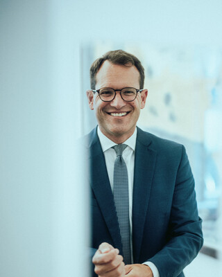 Ein lächelnder Herr in Geschäftskleidung hat seine Hände zu Fäusten geballt.