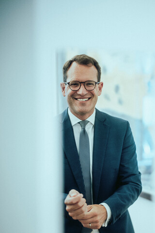 Ein lächelnder Herr in Geschäftskleidung hat seine Hände zu Fäusten geballt.