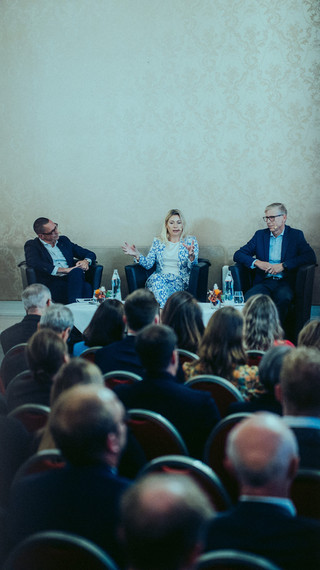 Publikum lauscht einer Podiumsdiskussion in einem historischen Saal.